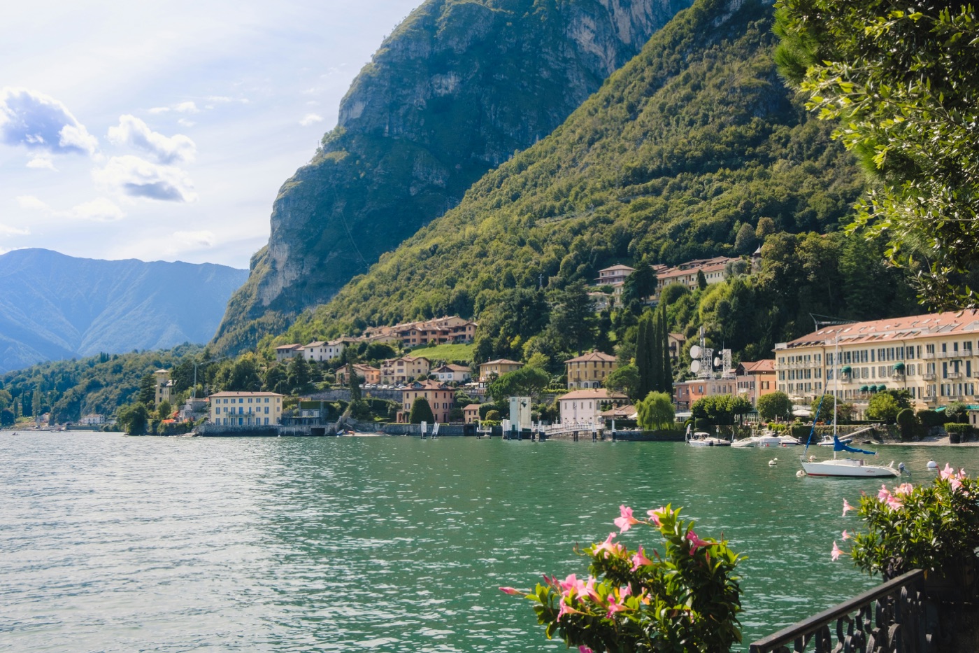Boats and lakeside buildings beneath green mountains at Lake Como, Italy